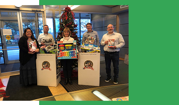 GTI Energy employees holding toys next to our Toys For Tots donation boxes