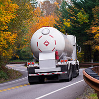 Rear view of a Liquefied Petroleum Gas (LPG) tanker truck driving down a road.