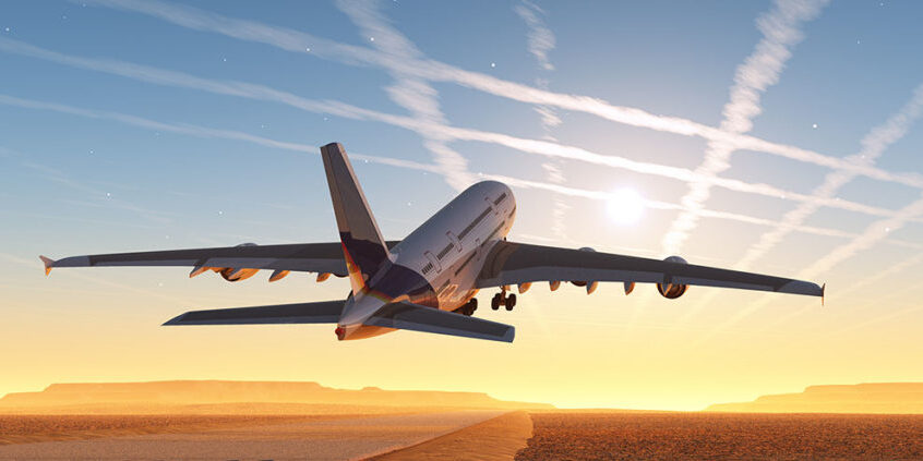 large commercial airplane flying towards a sunset